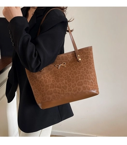 Detailed view of leopard print tote bag with golden bow and reinforced metal rivets