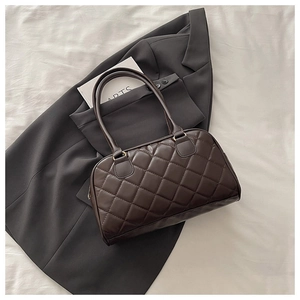 Dettaglio di una borsa tote trapuntata marrone scuro con spalline sottili su sfondo moda