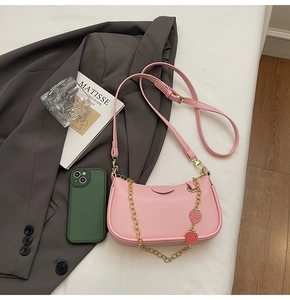 Detailed view of pink pebble grain bag with gold strawberry chain and leather strap