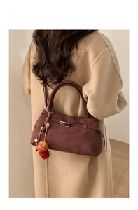 Detail of dark brown faux suede tote bag with decorative metal buckle and colorful pom charms