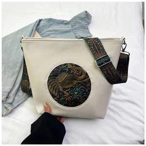 Detail of vintage beige bucket bag featuring elephant embossed medallion and ethnic strap