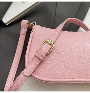 Close-up of pink litchi grain leather bag with elegant golden metal buckle and stitching
