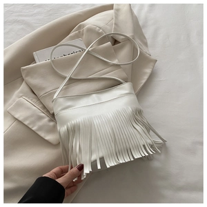 Detailed close-up of a white faux leather shoulder bag with long bohemian tassels