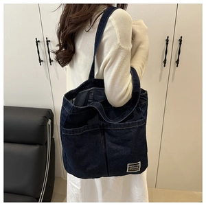 Macro detail of dark blue denim tote bag with two front pockets and chic label