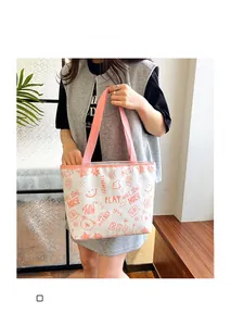 Detail of canvas tote bag featuring orange graffiti prints and pink ribbon handles