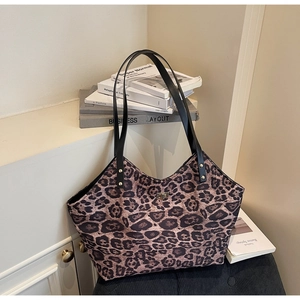 Detail of leopard print tote bag featuring a metallic twist lock and black leather straps