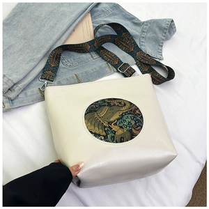 Detail of vintage elephant embroidery on an ivory bucket bag with colorful woven strap
