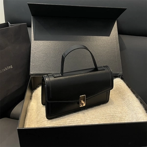Elegant black leather handbag with gold metal lock presented in a luxury gift box