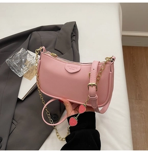 Close-up of pink underarm bag featuring strawberry charms and gold chain detail
