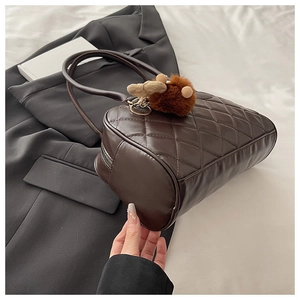 Vista dettagliata della borsa bowling trapuntata marrone scuro con ciondolo peluche
