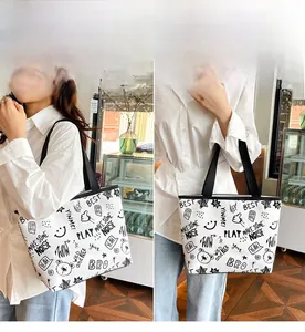Detail of white canvas tote bag with black street style graffiti and durable dual straps