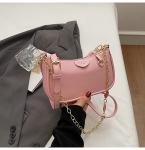 Detail of pink lychee textured leather baguette bag with golden chain and shoulder strap