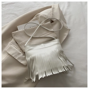 Close-up of white tassel shoulder bag with smooth faux leather texture and fringe detail