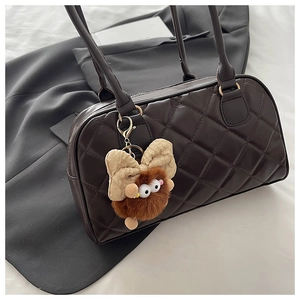 Dettaglio borsa bowling trapuntata marrone scuro con charm di peluche e fibbie d'oro