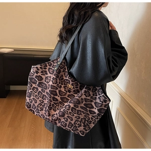 Detail of leopard print tote bag with black shoulder straps and metallic side buckle lock
