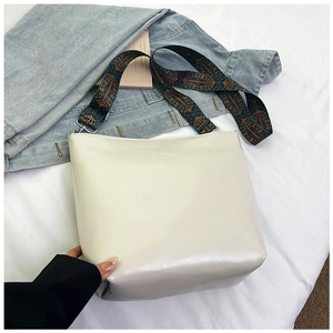 Detail of white leather bucket bag with vibrant bohemian embroidered wide shoulder strap