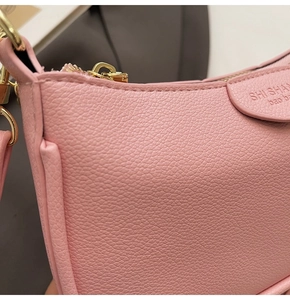 Detail of pink pebbled leather shoulder bag featuring gold-toned metal hardware and zipper