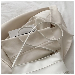 Detail of white minimalist shoulder bag with soft pleats on premium fabric texture