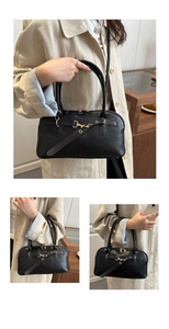 Detail of black textured leather shell bag showing gold metal hardware and buckle