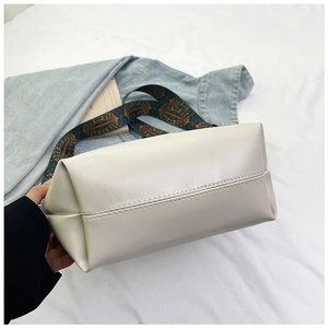Detailed view of white leather tote bag bottom featuring clean stitching and ethnic strap