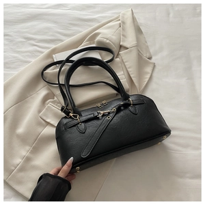 Detail of black lychee-textured Boston bag with gold hardware on a beige blazer