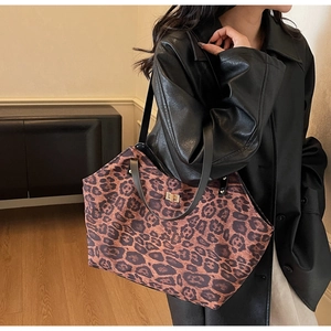 Close-up of leopard print tote bag with black leather straps and gold metal twist lock