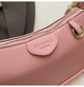 Detail of pink lychee leather handbag featuring gold zipper and embossed brand logo