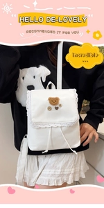 Detail of white nylon backpack with lace trim and cute brown bear embroidery