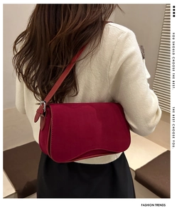 Detail view of burgundy matte leather shoulder bag worn over a white knit sweater