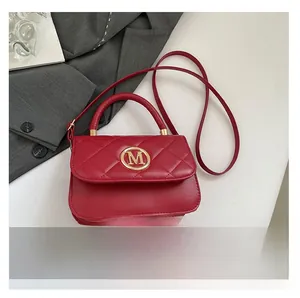 Bolso rojo acolchado con cierre M dorado junto a móvil para comparar tamaño