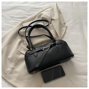 Detail of black lychee grain leather handbag with gold metal hardware and phone for size reference