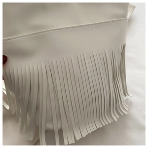 Close-up of white synthetic leather handbag featuring long tassel details and clean stitching