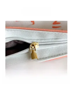 Detail of a gold metal zipper closure on a white textured fabric tote bag with prints