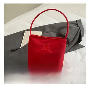 Détail du sac seau en toile rouge avec broderie Hope and Future sur blazer gris