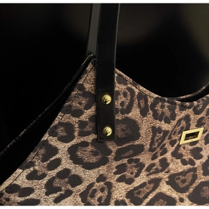 Detailed close-up of leopard print tote bag with black leather handle and gold rivets