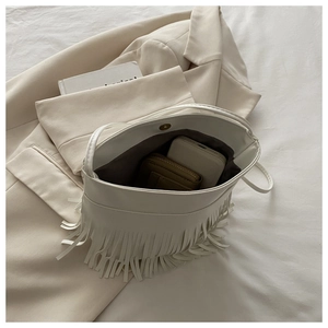 Detail showing white fringe crossbody bag interior with magnetic clasp and phone storage