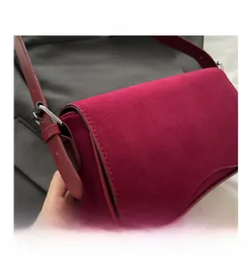 Detail shot of burgundy velvet shoulder bag with adjustable strap and metal hardware
