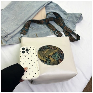 Detail of beige leather tote with ethnic elephant pattern inlay and wide woven strap