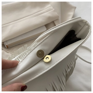 Detail of the white tassel handbag showing the gold magnetic closure and interior lining