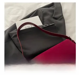 Detail of red suede rectangular shoulder bag with silver buckle on grey suit background