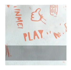 Detailed view of woven fabric texture with orange graffiti prints on a white tote bag