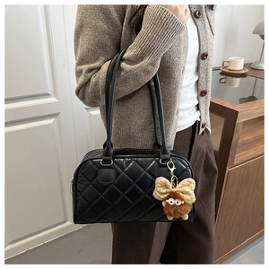 Dettaglio borsa bowling nera trapuntata con ciondolo di peluche e texture in pelle sintetica