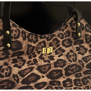 Detail of leopard print tote featuring a gold twist lock and black leather handle