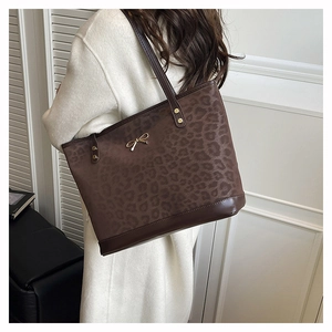 Detail of leopard print tote bag with gold bow buckle on model in minimalist setting