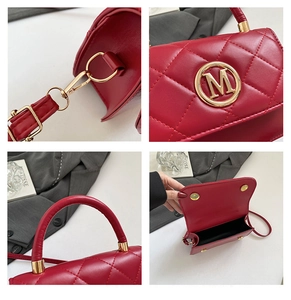 Detail view of red quilted bag featuring gold metal M logo and high-quality hardware
