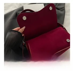 Detail shot of the burgundy suede handbag featuring double magnetic snap closures