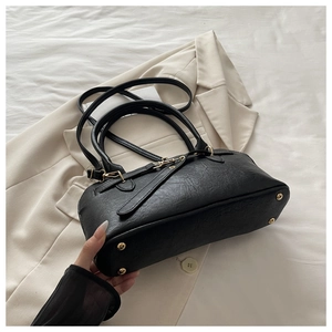 Detail of black pleated leather handbag with golden protective feet and hardware