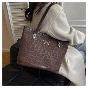 Detail of leopard print tote bag with golden bow ornament and slim leather shoulder straps