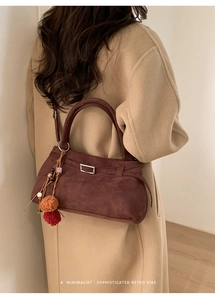 Macro shot of dark burgundy suede tote with metal buckle and plush pendant charm