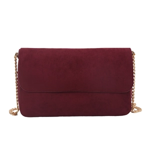 Minimalist burgundy suede crossbody bag with gold chain strap on white background